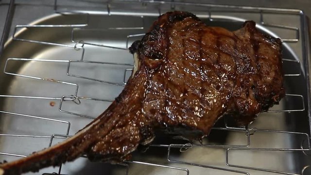 Big Tomahawk steak with bone.Cook sprinkles steak with spices..