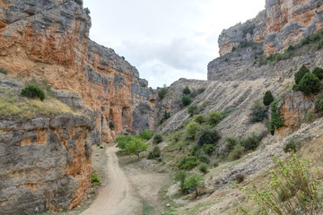 The Barranco de la Hoz Seca (Dry Defile Gully) canyon, with scarps, bushes and red rocks, in a cloudy atumn, in the Jaraba rural town, Aragon, Spain