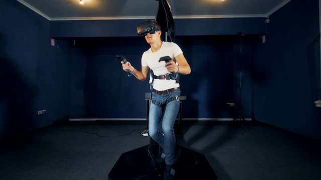 A young man in VR mask is walking while being in a simulation