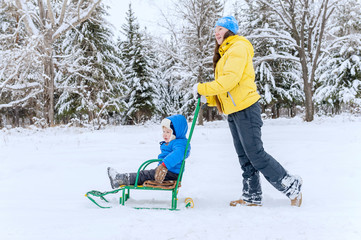 Outdoor portrait Mum walks with the child in the winter. She rol