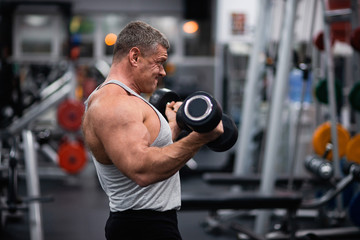 Fototapeta na wymiar athletic man trains in the gym. Training biceps with a dumbbells
