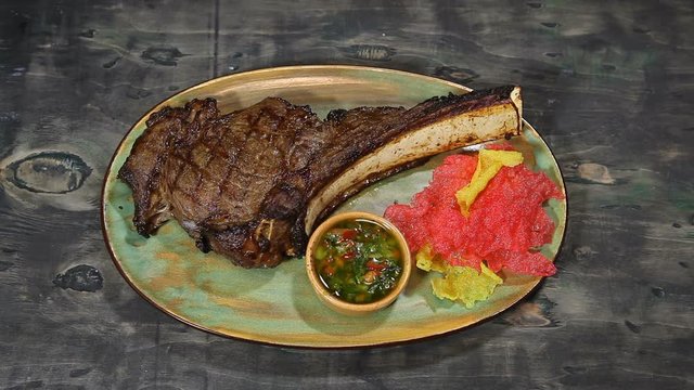 Tomahawk steak.The cook serves a tomahawk steak with rice chips and garlic sauce.