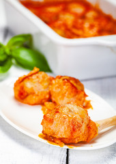 Meatballs with tomato and sour cream sauce on white plate. Close up
