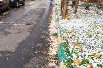road and lawn covered by the first snow in city