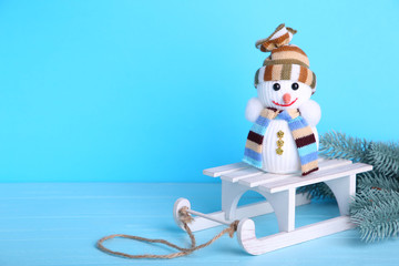 Small snowman with white sleigh on blue background