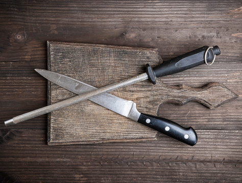  old brown wooden cutting board and knife with sharpening