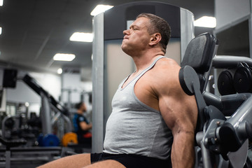 Fototapeta na wymiar athletic man trains in the gym. Training of biceps