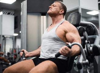 Fototapeta na wymiar athletic man trains in the gym. Training of biceps