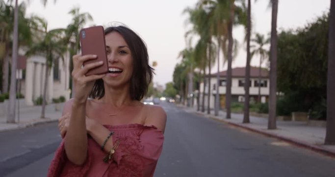 Stylish young woman takes selfies in middle of californian street