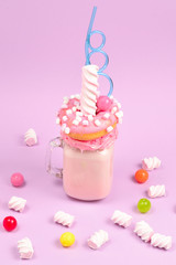 Pink strawberry freakshake with marshmallow and sweets.