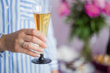 women's hand holding a glass of champagne on the background of the festive table