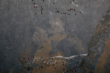 top view of scattered salt and allspice on grey marble background