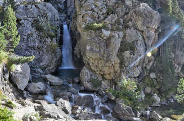 A Caldarès river waterfall during a sunny autumn in the firs and pine trees forest of the rocky mountains of Panticosa, Aragon Pyrenees, Spain