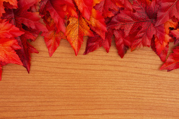 Obraz premium Autumn background with red and orange fall leaves on wood