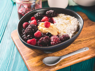 Vegan cashew milk Chia pudding with berries and home made almond butter served in a bowl on wooden board