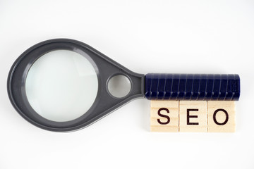 SEO, Search Engine Optimization word collected of wooden elements with the letters and also magnifying glass.