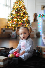 Ребенок ждет чуда в Новый год. С новым годом! Счастливого Рождества! Новогодняя елка с рождественскими игрушками. Девочка  с подарками.
