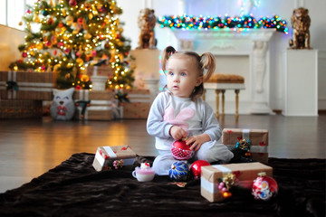 Ребенок ждет чуда в Новый год. С новым годом! Счастливого Рождества! Новогодняя елка с рождественскими игрушками. Девочка  с подарками.
