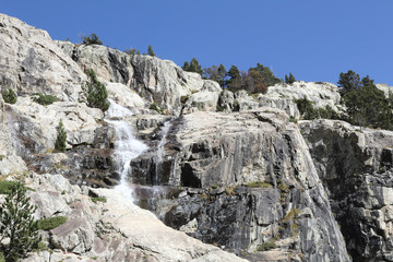 A Caldarès river waterfall during a sunny autumn in the firs and pine trees forest of the rocky mountains of Panticosa, Aragon Pyrenees, Spain