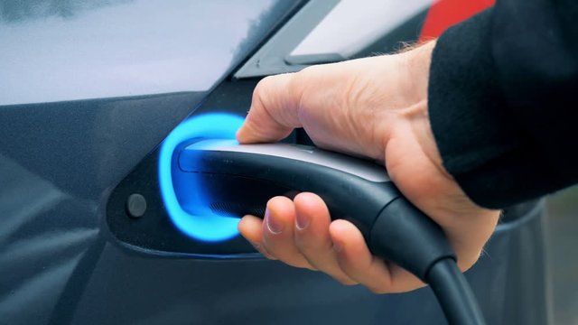 Person charging an electromobile, close up.