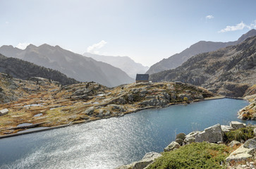 A lodge in the Balchimaña artificial lake, among barren rocky mountains and a blue sky in a sunny...