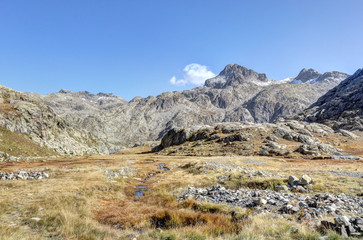 A landscape of the high rocky mountains with barren soil, yellow grass and a deep blue sky in a sunny autumn, in Panticosa, Aragon Pyrenees, Spain