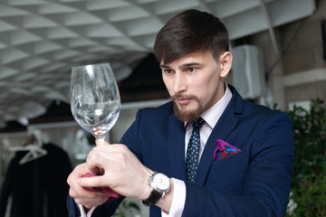 young male sommelier holds a glass of red wine while tasting wine
