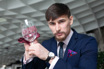 young male sommelier holds a glass of red wine while tasting wine