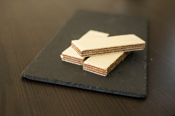 Wafers with chocolate on black slate board, close-up