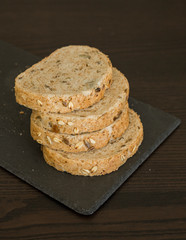 Slices of homemade multigrain bread on black slate board