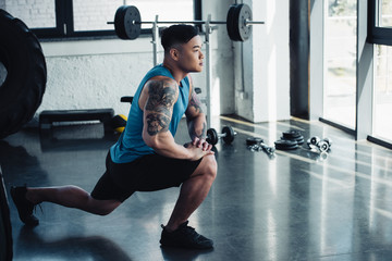focused young sportsman doing lunge exercise at gym
