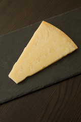 Slice of cheese on black slate board, close-up