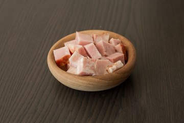 Pieces of baked ham in bowl on wooden background,