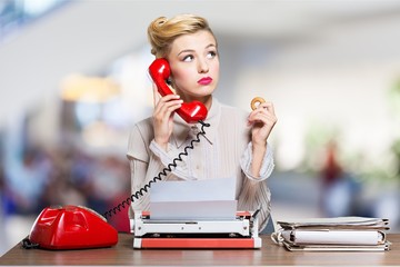 Young secretary with red phone and typing - obrazy, fototapety, plakaty