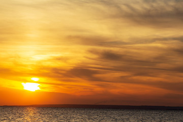 background of sunset on the sea, birds fly among the clouds lit by the rays of the sun