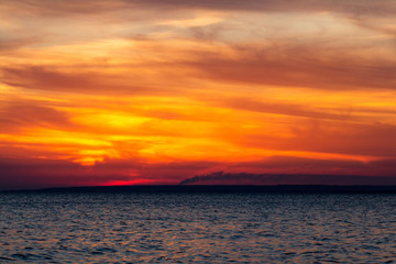 background of sunset on the sea, birds fly among the clouds lit by the rays of the sun
