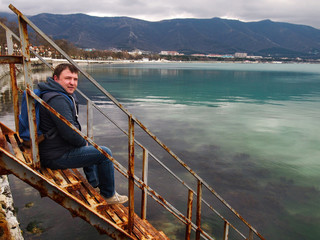 a man sits on an old staircase that goes deep into the water surface