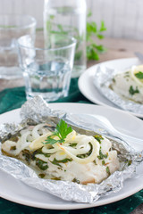 Cod baked in herbs and onions in foil, selective focus
