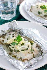 Cod baked in herbs and onions in foil, selective focus