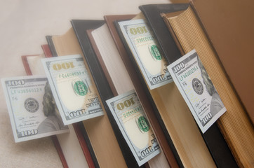 a stack of books, in them dollars, bookmark
