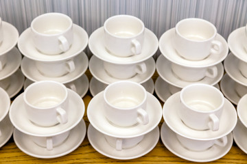 Lot of white porcelain tea pairs in piles in a straight line. Concept conference at the hotel, break, catering, breakfast