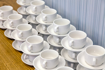 Lot of white porcelain tea pairs in piles in a straight line. Concept conference at the hotel, break, catering, breakfast
