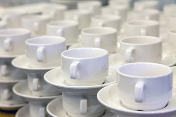Lot of white porcelain tea pairs in piles in a straight line. Concept conference at the hotel, break, catering, breakfast