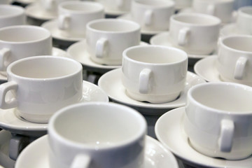 Lot of white porcelain tea pairs in piles in a straight line. Concept conference at the hotel, break, catering, breakfast