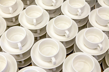 Lot of white porcelain tea pairs in piles in a straight line. Concept conference at the hotel, break, catering, breakfast