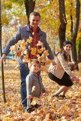 Happy family is in autumn city park. Children and parents. They posing, smiling, playing and having fun. Bright yellow trees.