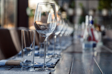 Restaurant serving and glass wine and water glasses, forks and knives on textile napkins stand in a row on a gray wooden table. Concept banquet, birthday, conference, group lunch