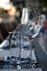 Restaurant serving and glass wine and water glasses, forks and knives on textile napkins stand in a row on a gray wooden table. Concept banquet, birthday, conference, group lunch