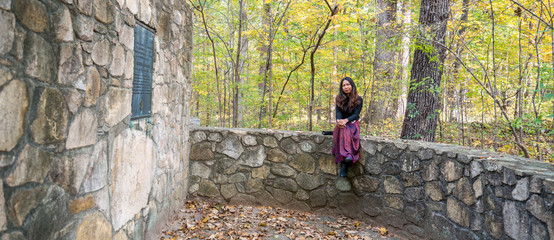 Woman in sarong sitting on stone wall in amphitheater