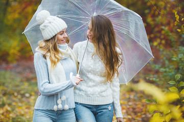 Young pretty girls having fun outdoors in autumn background. Cheerful friends in the fall time